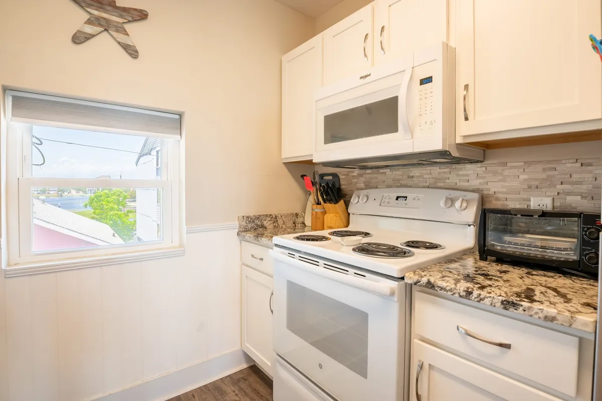 A modern kitchen outfitted with stainless steel appliances, granite countertops, and a window offering natural light. The kitchen is organized and inviting, ideal for cooking and socializing with family or friends.