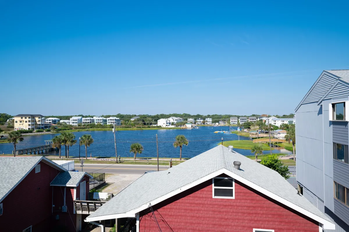 This image displays a waterfront view framed by palm trees and colorful houses in the background. The area is ideal for casual strolls, boating, or relaxing by the water, capturing the relaxed charm and community spirit of Carolina Beach.